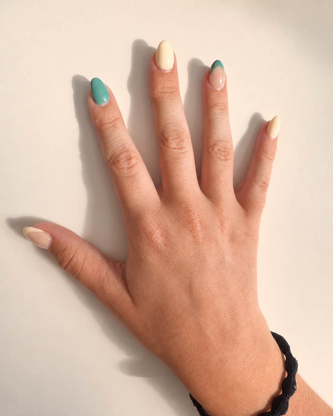 Mixed teal, yellow, and green French-tip almond nails on one hand